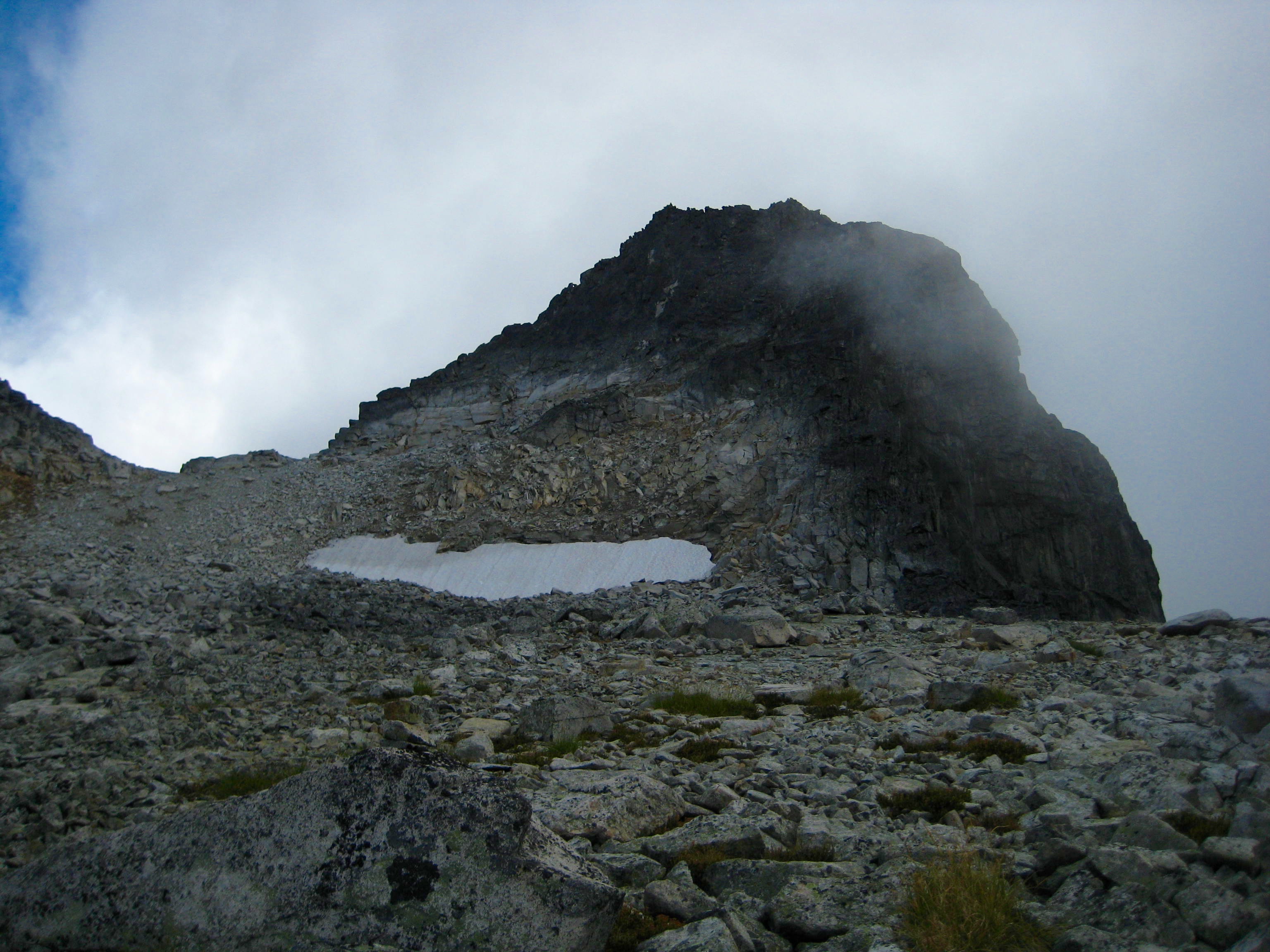 scree field with snow patch below the rocky summit of Bear Mountain in the American Chilliwacks