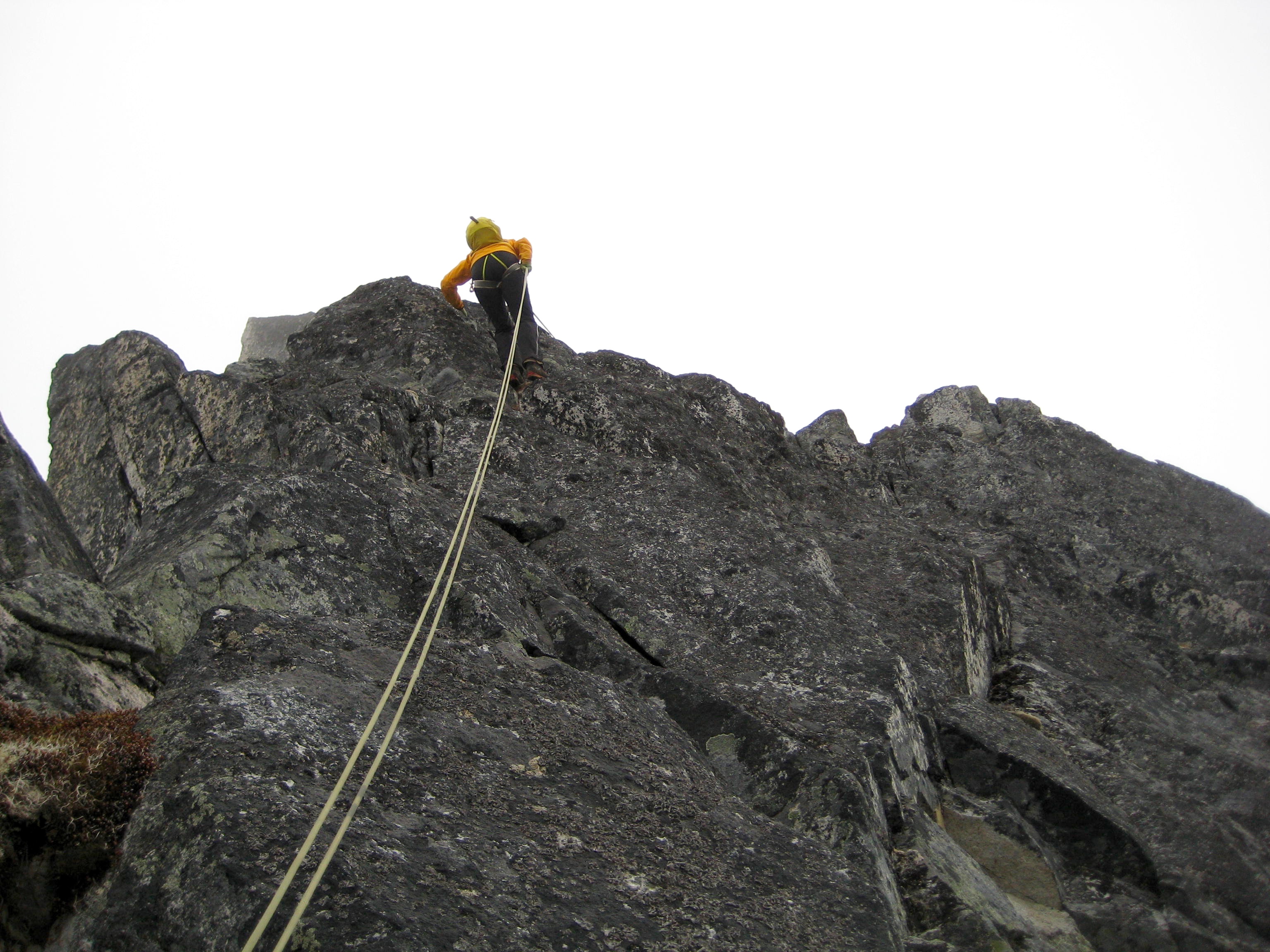 mountain climber starting a roped rappelling from high on the north ridge of rocky Bear Mountain in the American Chilliwack