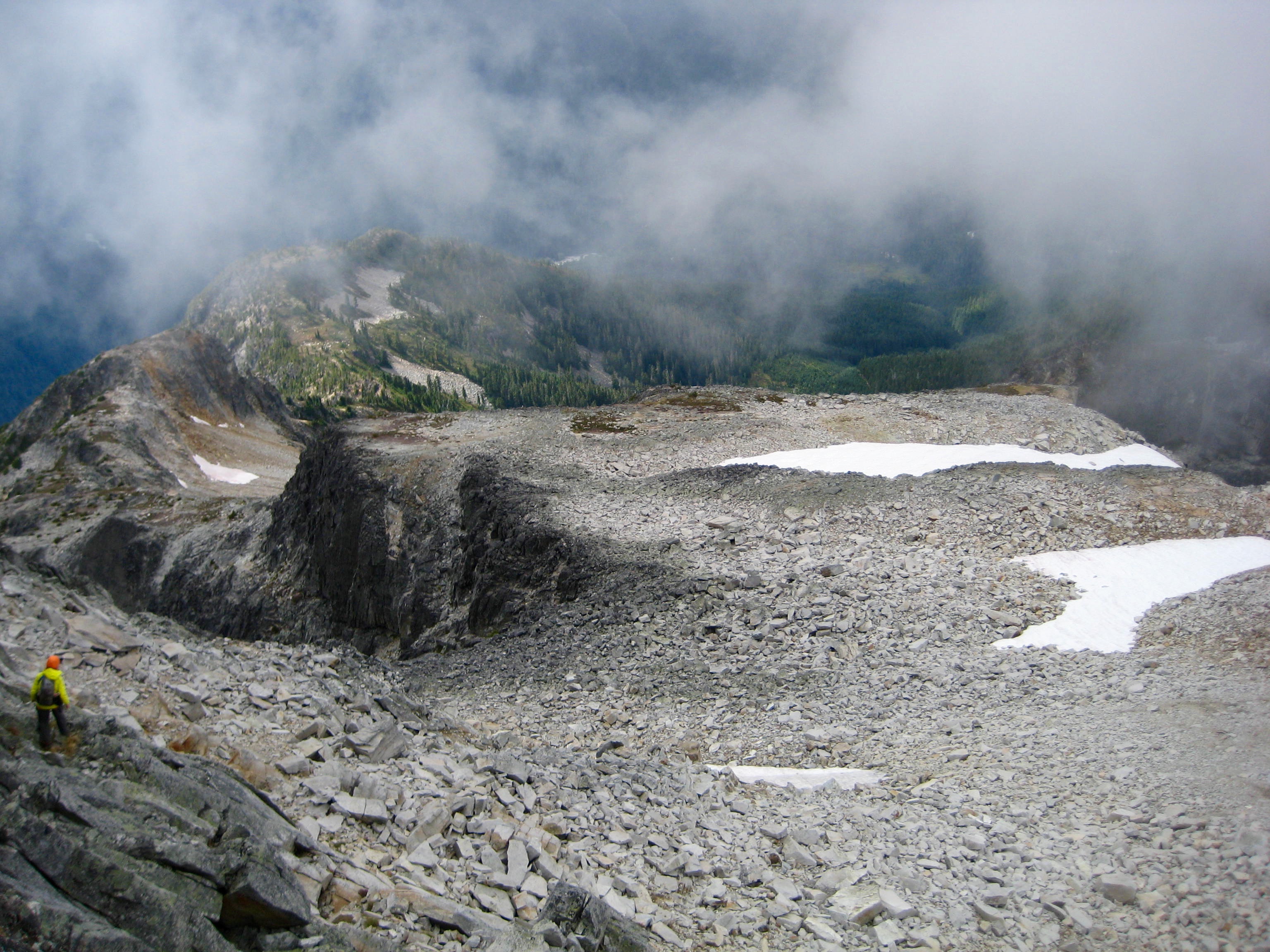 mountain climber descending the rocky scree and the west ridge of Bear Mountain in North Cascade National Park in the high fog