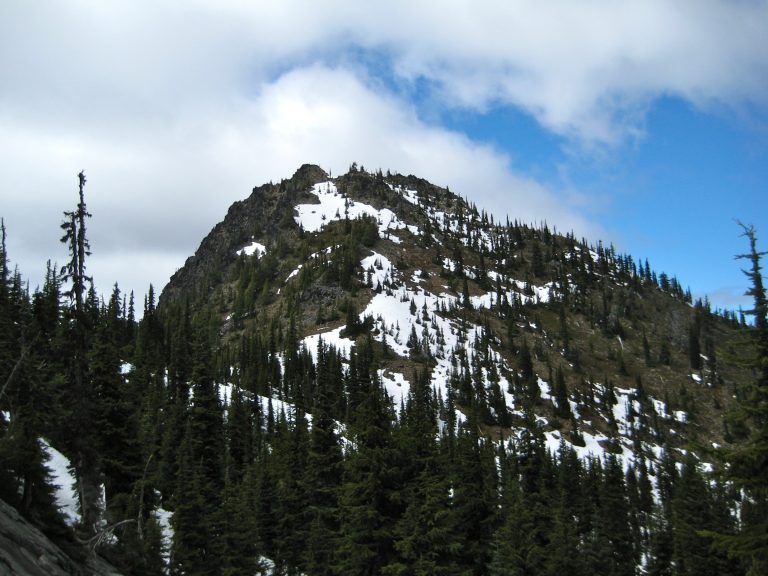 Southeast Dirtyface Peak rises above a forest ridge on Dirtyface Mountain