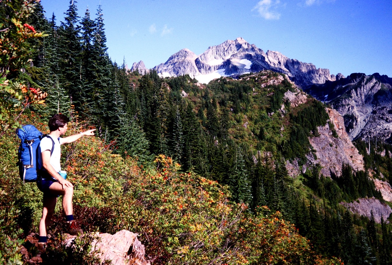 A mountain climber points toward Columbia Peak in the Monte Cristo Mountains
