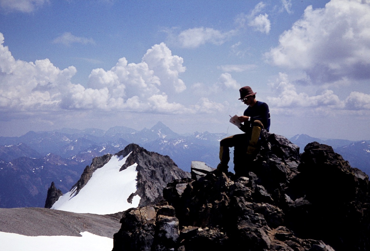 A mountain climber sits on the rocky summit of Mt Daniel in the Snoqualmie Mountains