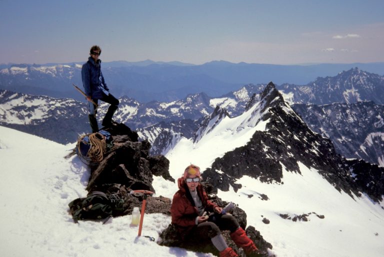Mountain climbers on the rocky, snow patched summit of Clark Mountain in the DaKobed Range in the Glacier Peak Wilderness