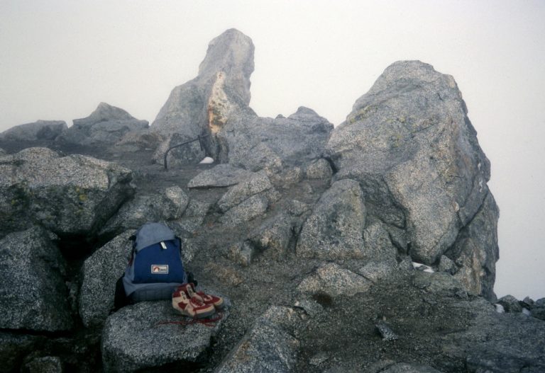 A backpack and boots sit on the foggy summit of Mt Pugh in the Cascade Mountains