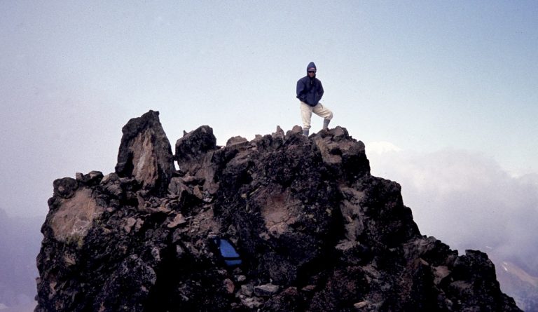 A mountain climber stands on the summit of Mt Curtis Gilbert in the Goat Rocks Wilderness