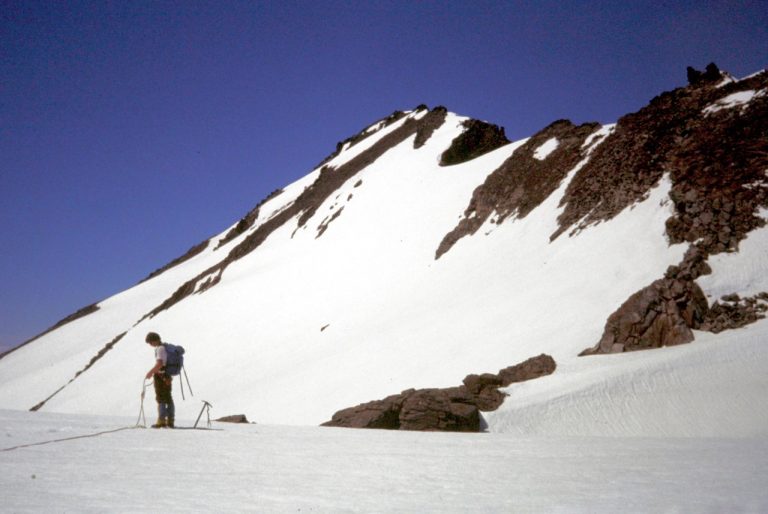 A mountain climber stands on the Walrus Glacier below the summit of Clark Mountain in the Glacier Peak Wilderness