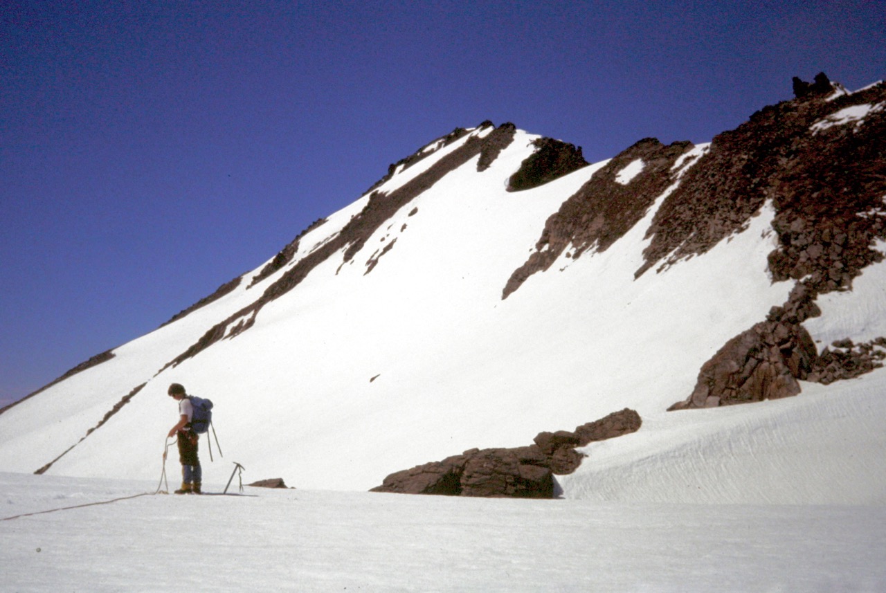A mountain climber stands on the Walrus Glacier below the summit of Clark Mountain in the Glacier Peak Wilderness