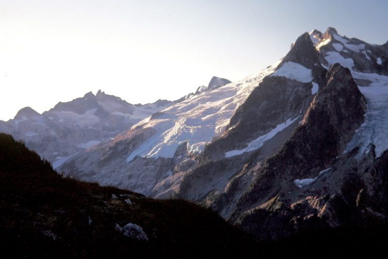 Morning sun lights up Gunsight Peak and Chikamin Glacier and Dome Peak from camp at White Rock Lakes during the Ptarmigan Traverse