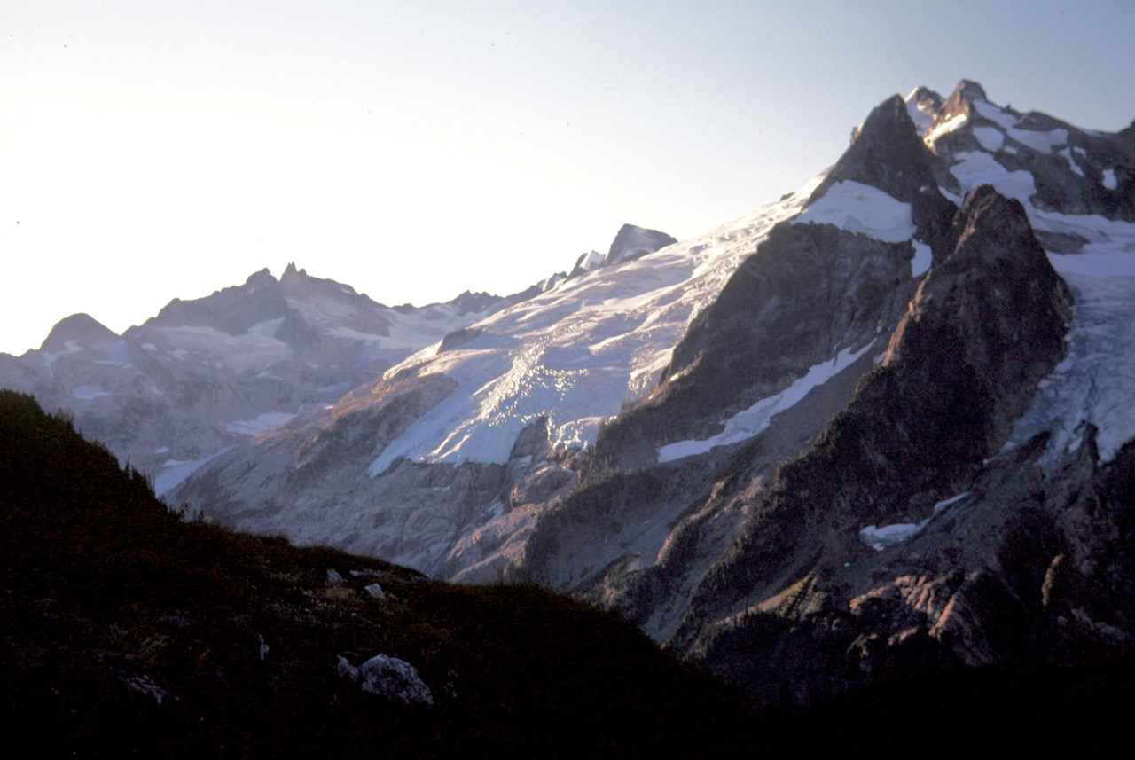 Morning sun lights up Gunsight Peak and Chikamin Glacier and Dome Peak from camp at White Rock Lakes during the Ptarmigan Traverse