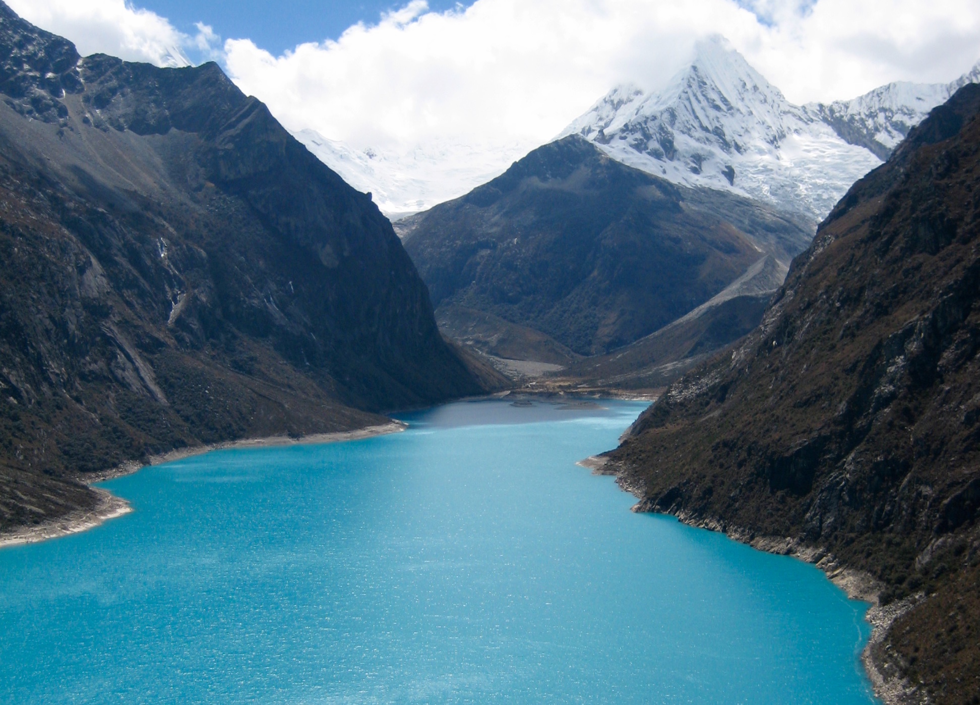 Turquoise colored Lake Paron reclines in a deep valley below snowy Cordillera Blanca mountains of Peru