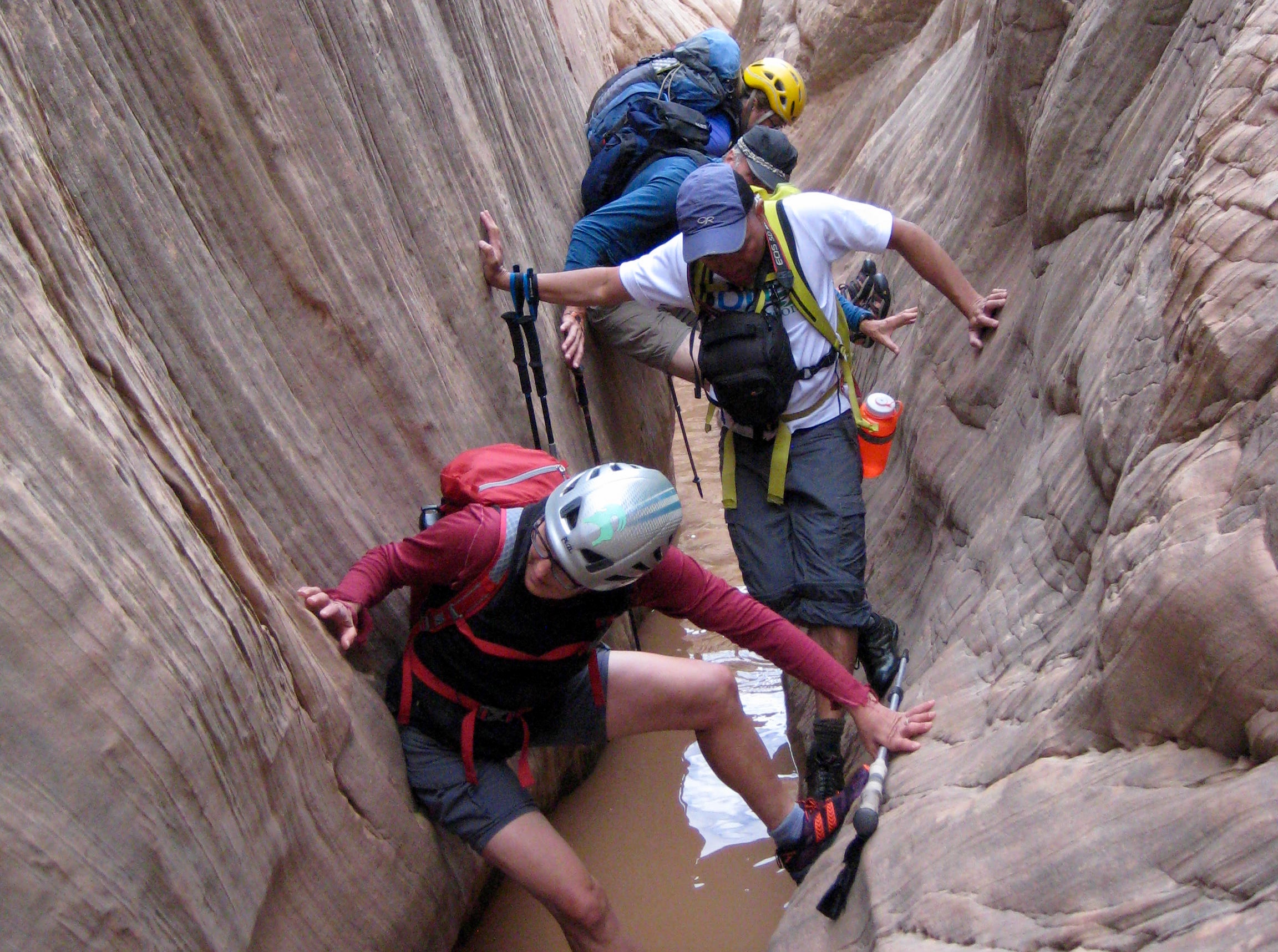 A group of canyoneers scrambles through a narrow slot in Dang Canyon in Utah