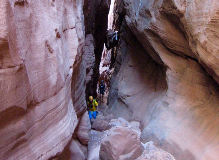 Canyoneers scramble through a narrow slot in Main Fork Bluejohn Canyon in the Robbers Roost Area of Utah