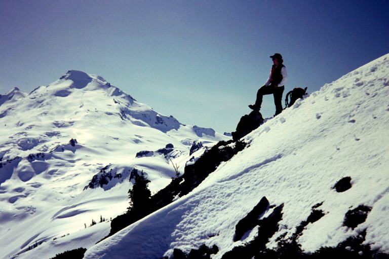 Mt Baker stands behind a lone climber on Coleman Pinnacle