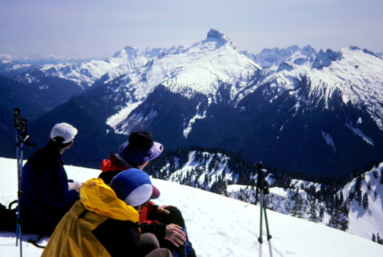 Snowshoers on summit of Breccia Peak look over at lofty Sloan Peak