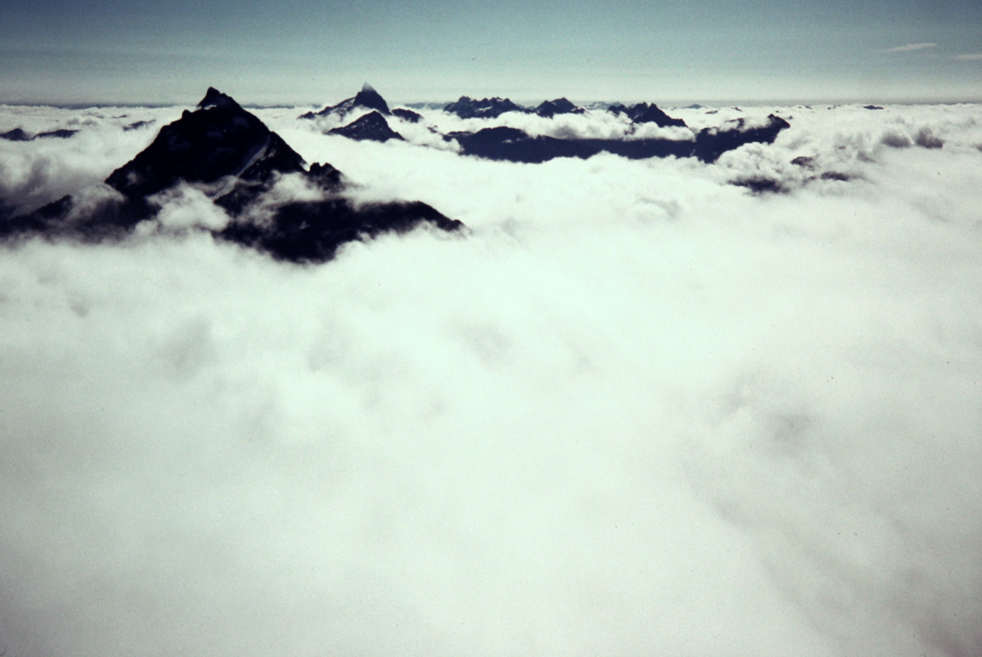 The sharp summits of Mt Pugh and Sloan Peak poke upward through a sea of clouds seen from White Chuck Mtn