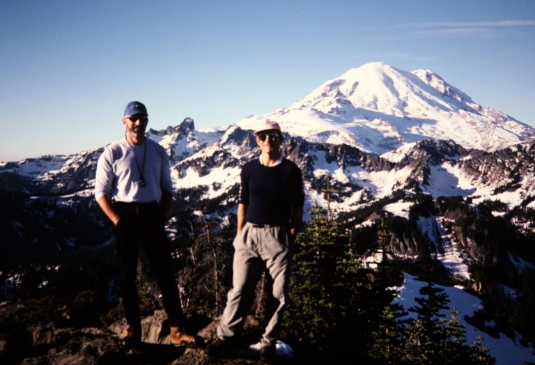 Two climbers stand on Yakima Peak summit with Mt Rainier behind them