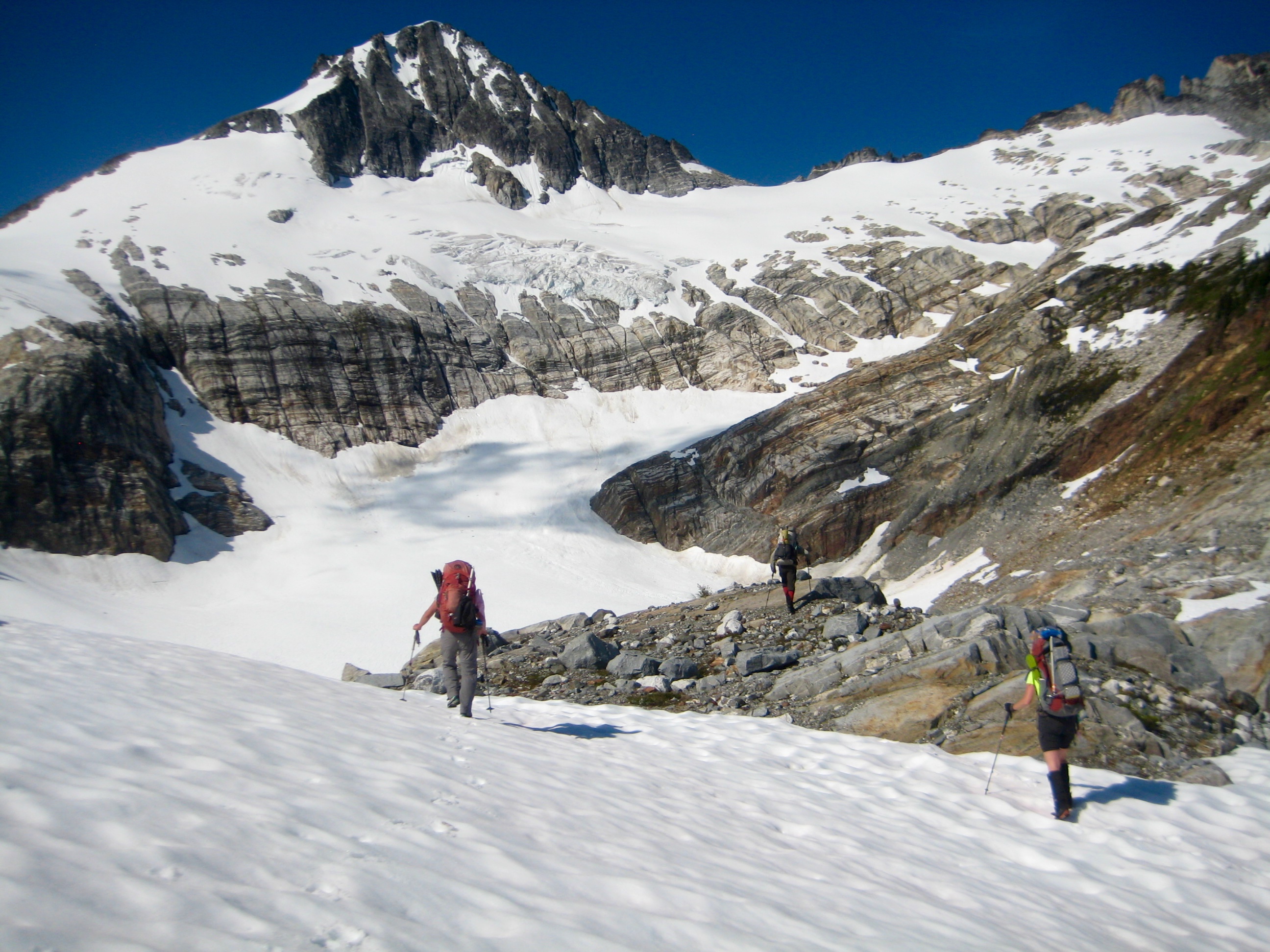 Mountain climbers booting across snow field toward Borealis Glacier and Primus Peak in the North Cascades