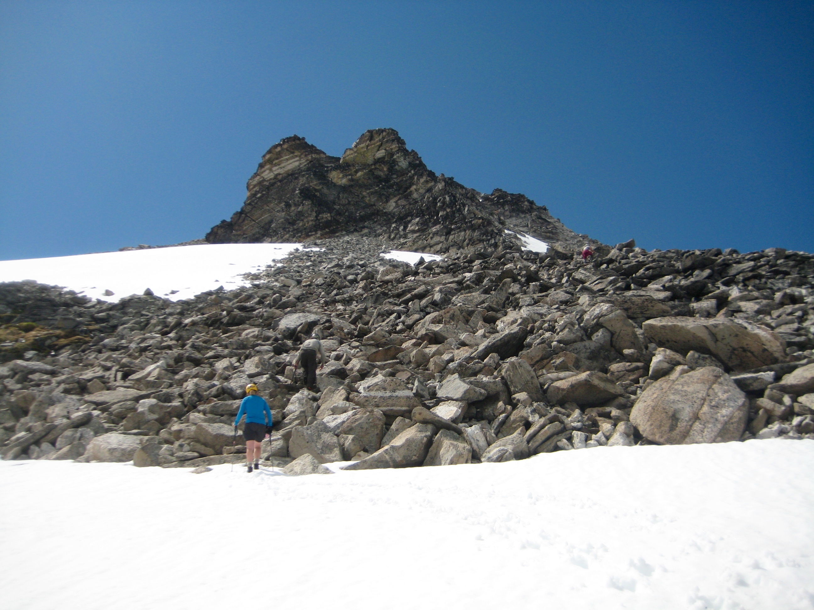 Mountain climber booting up snow and boulders on Primus Peak in the North Cascades as seen from Borealis Pass and McAllister Traverse aka Inspiration Traverse