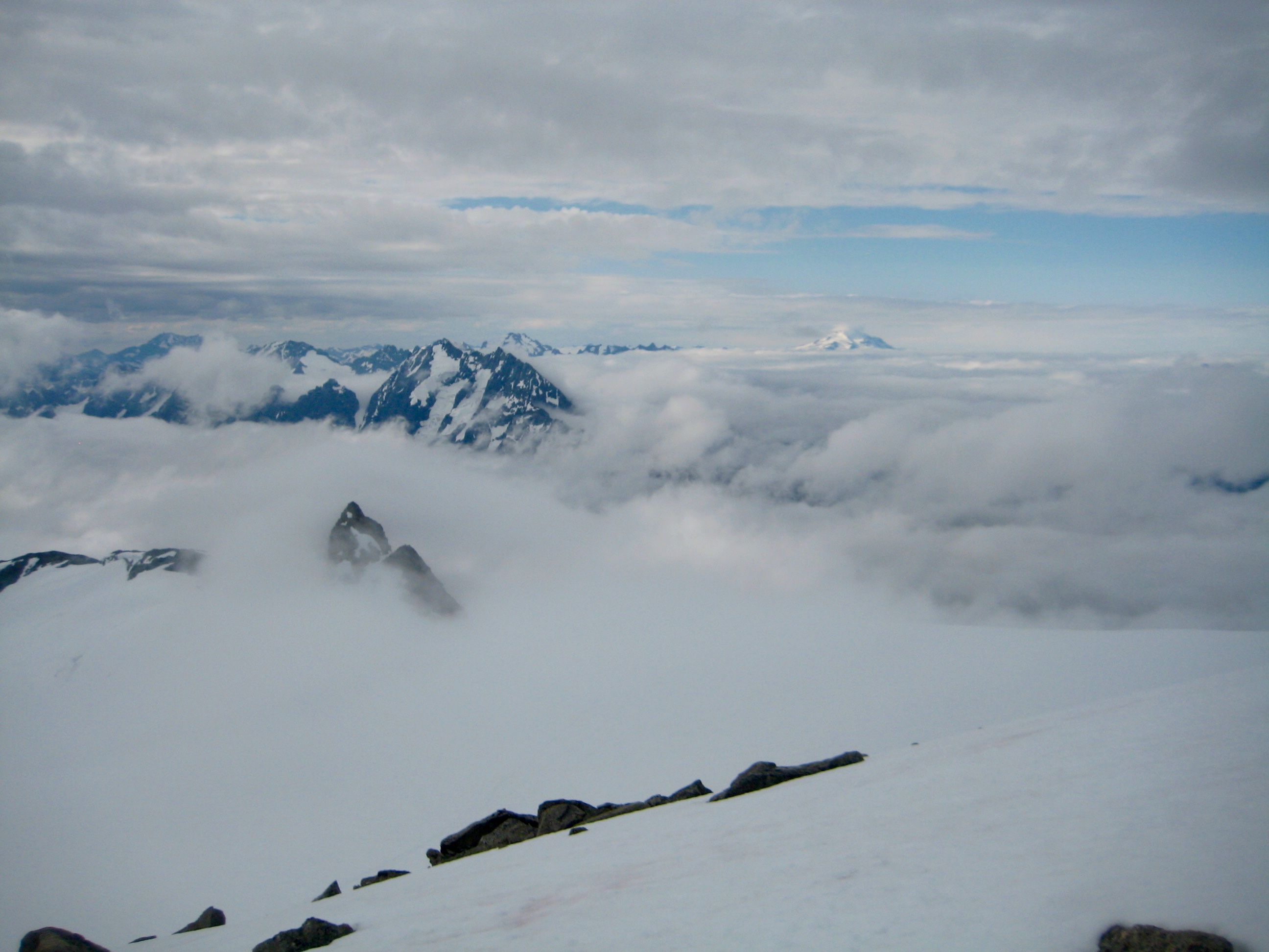 Morning Clouds and fog across Tepeh Towers and Dorado Needle above large snowfield from North Klawatti Notch on McAllister Traverse aka Inspiration Traverse