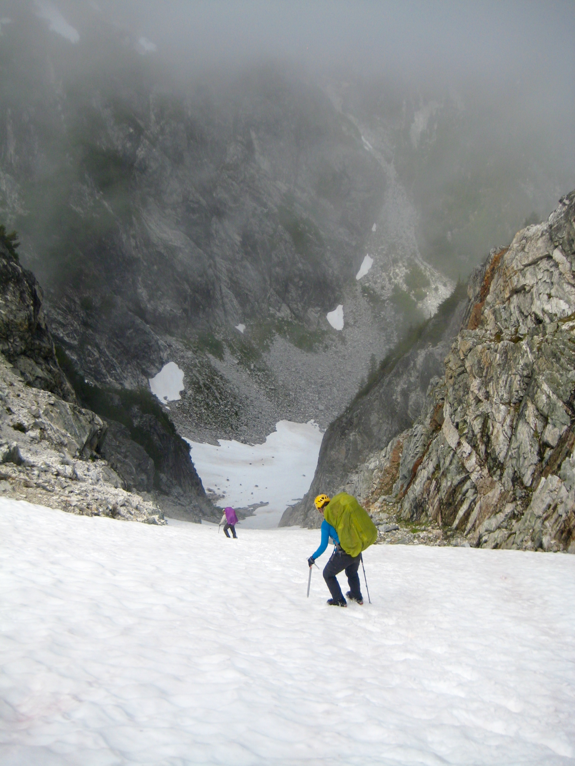 looking down on mountain climbers descending snow chute below Coccyx Col in the NOrth Cascades on McAllister Traverse aka Isolation Traverse