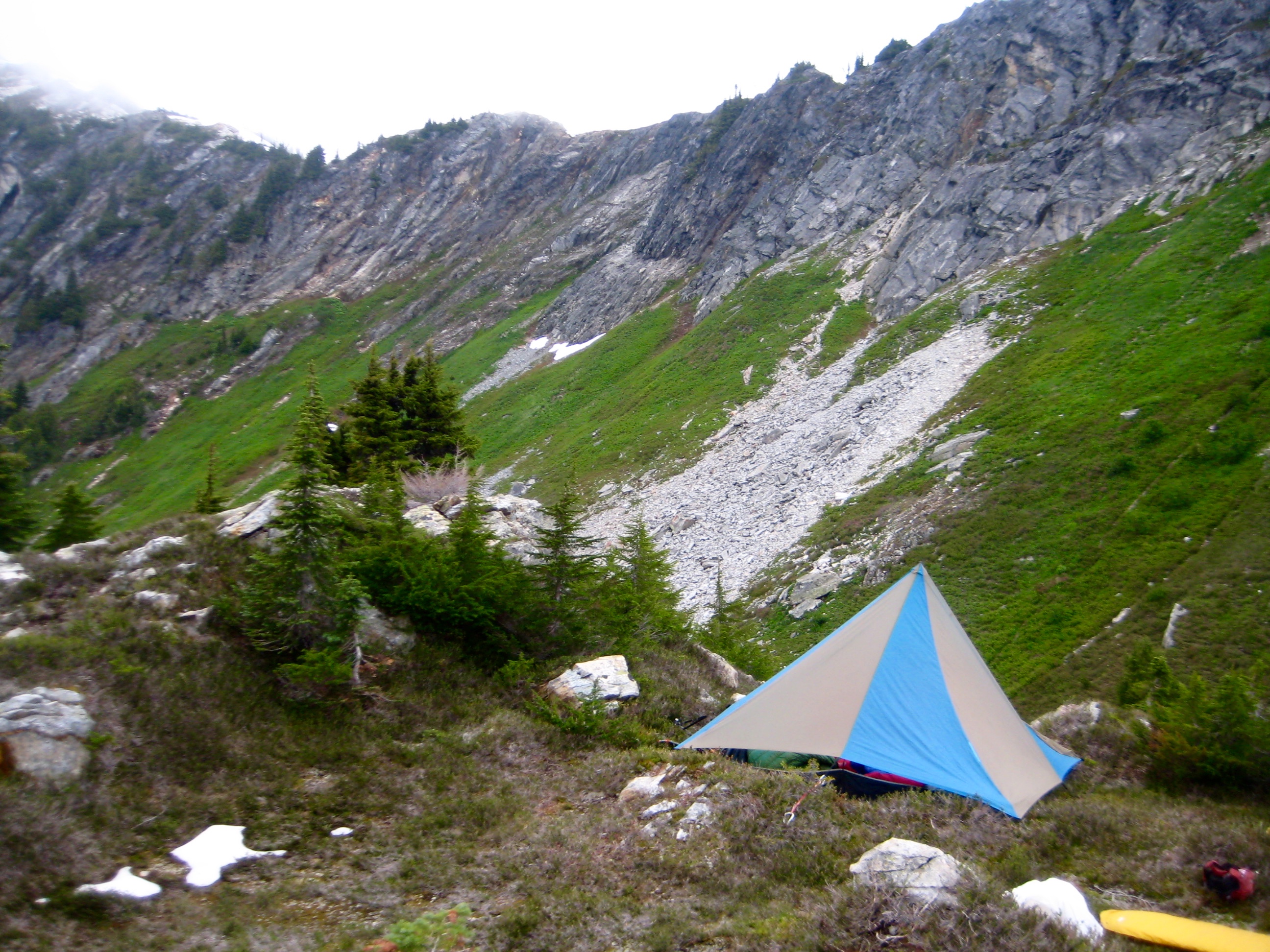 mountain climber's camp in the heather with a rocky ridge in the background along the Isolation Traverse in the North Cascades