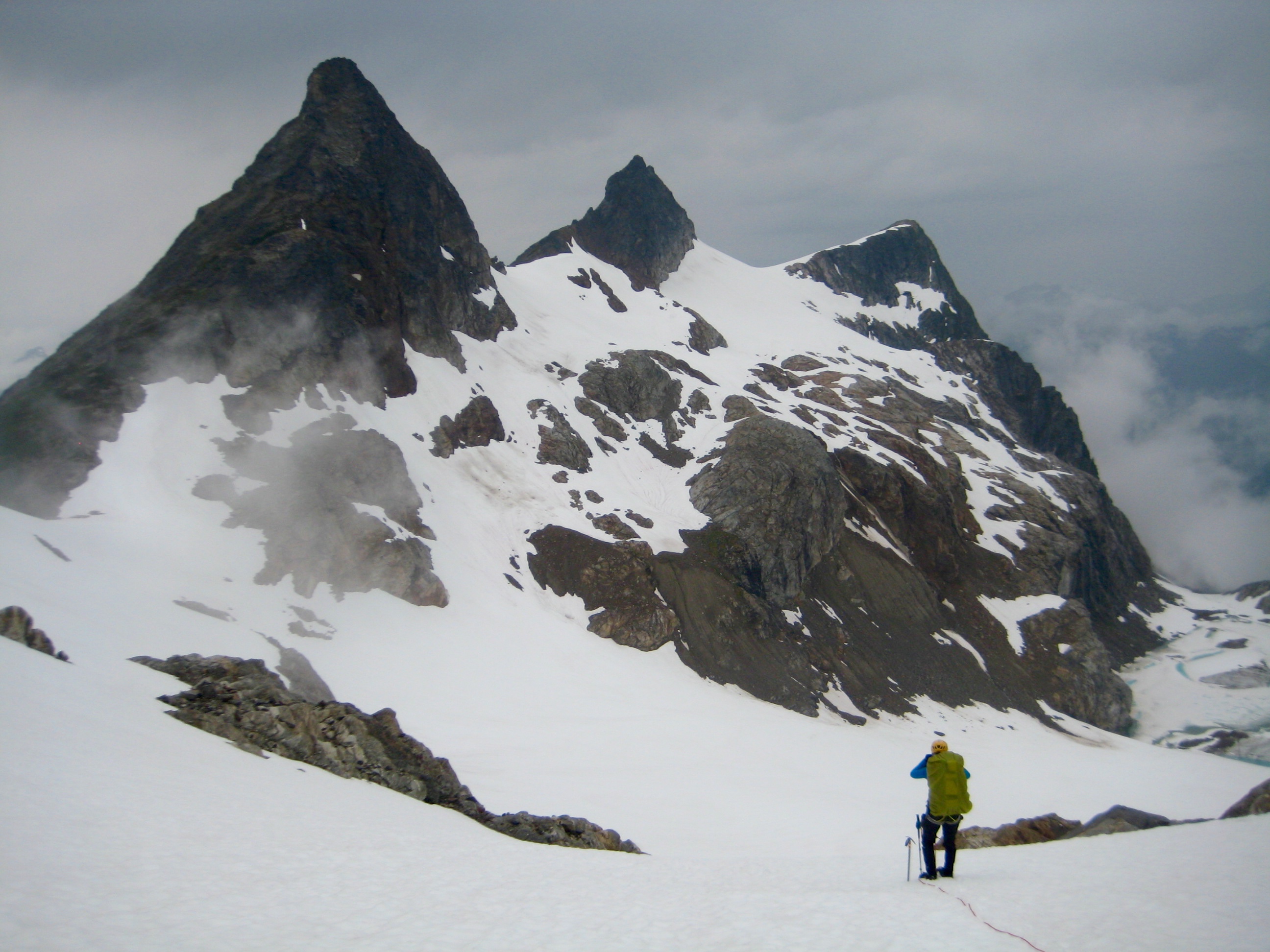 roped mountain climber on large snowfield below Paul Bunyans Stump, Pinnacle Peak, and Pyramid Peak in the North Cascades