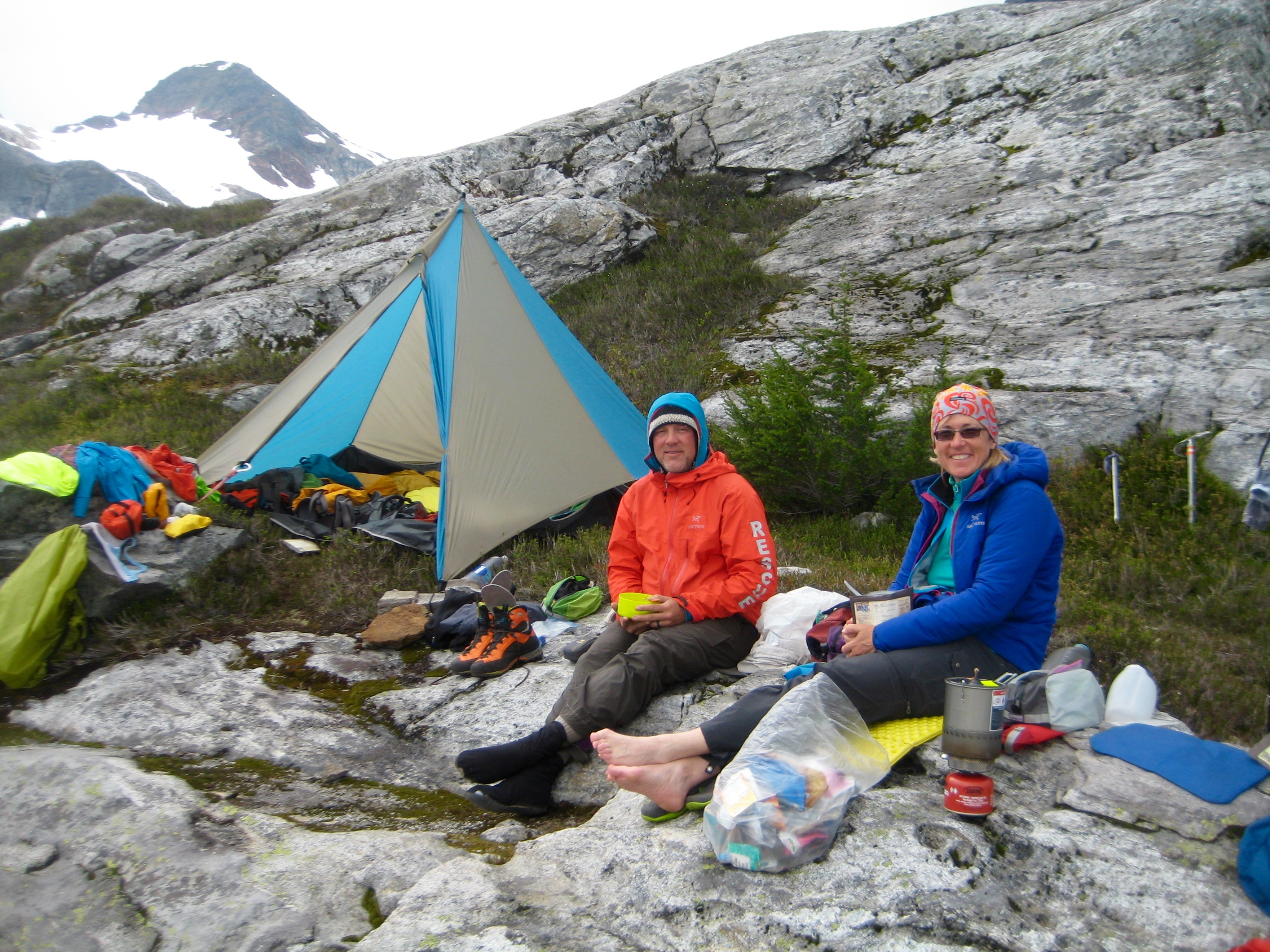 mountain climber's relaxing in camp on rock slabs and heather along the Isolation Traverse in the North Cascades