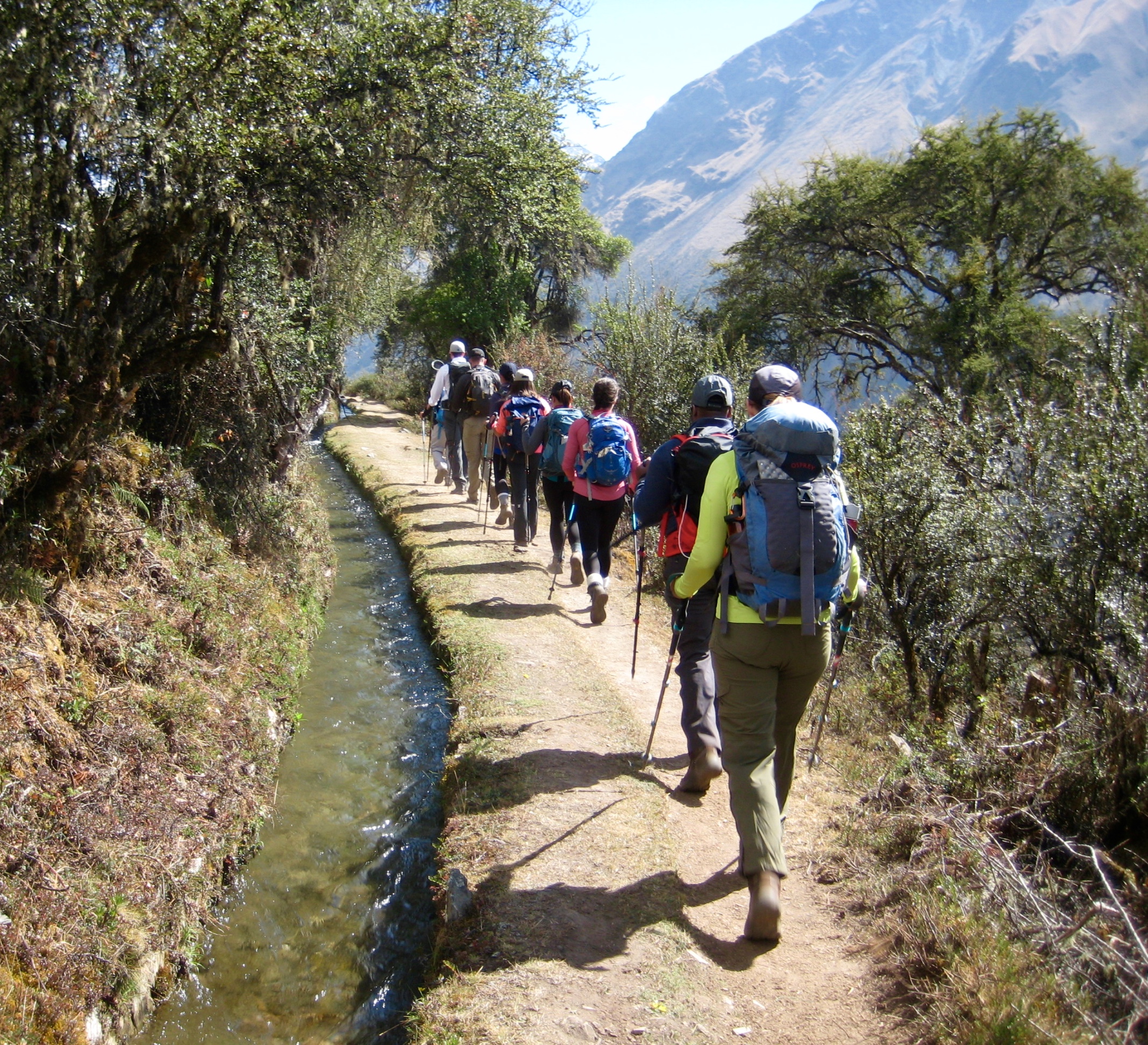 trekkers hiking along Inca Canal with snow covered mountains