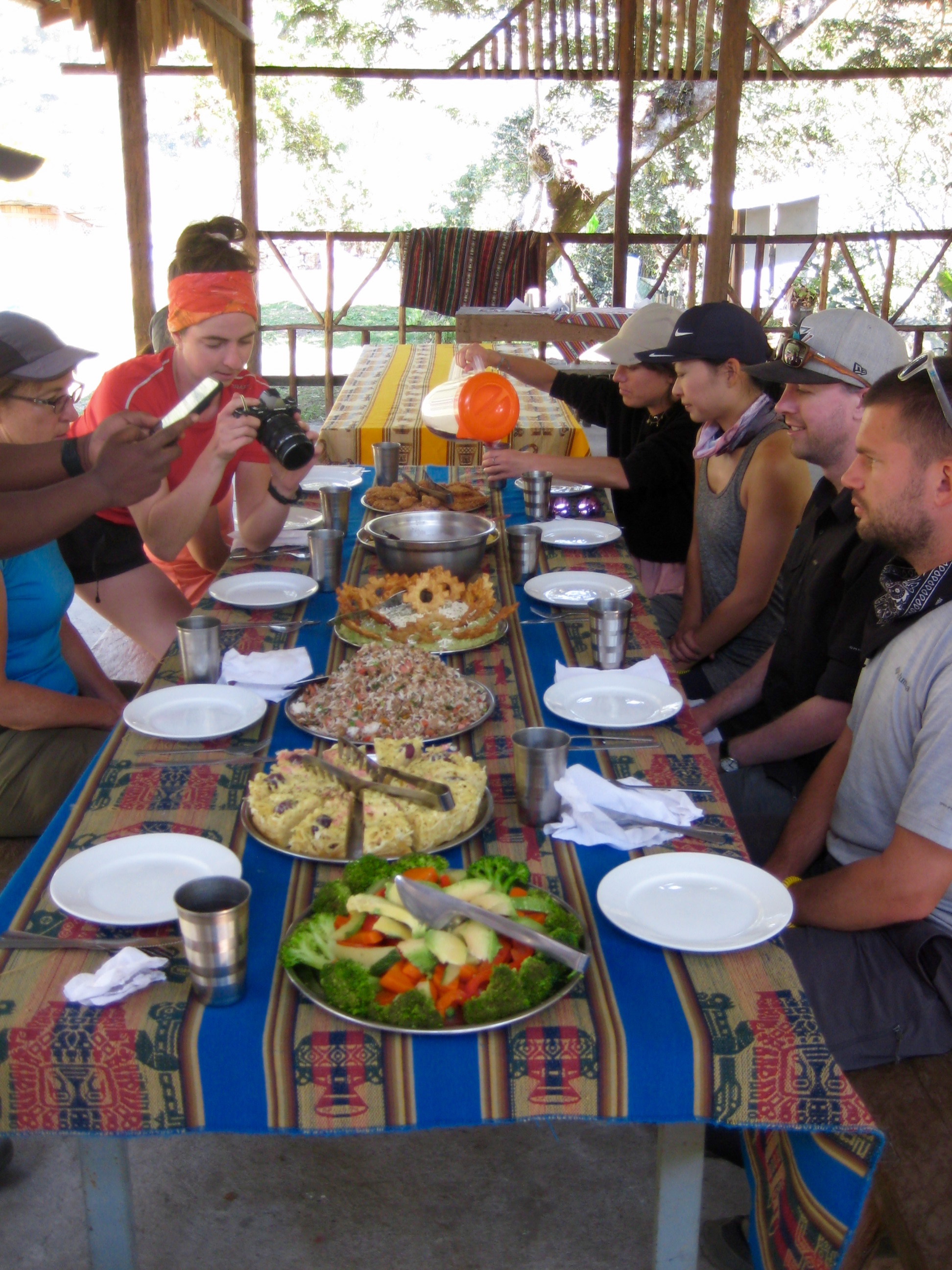 trekkers sitting at a picnic table with a lunch spread at Lucmabamba