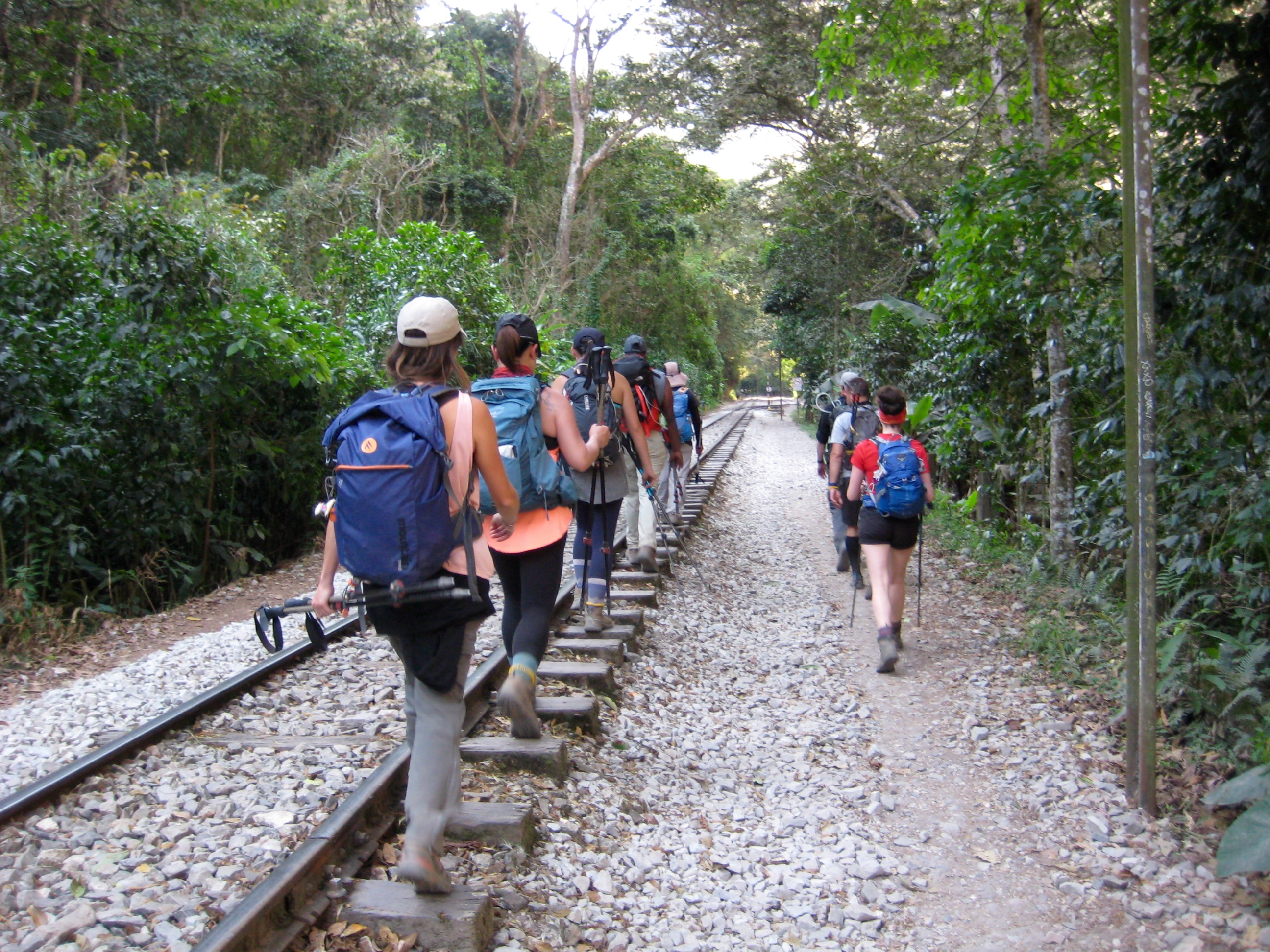 groups of trekkers power marching next to railroad tracks alongside the Urubamba river heading to Machu Picchu