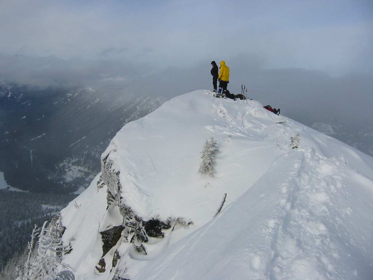 Three snowshoers stand atop a snowy Red Mountain