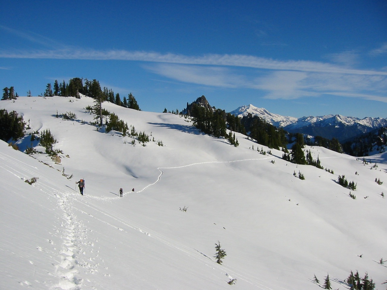 Snowshoers traverse a broad snowfield en-route to Pemmican Peak
