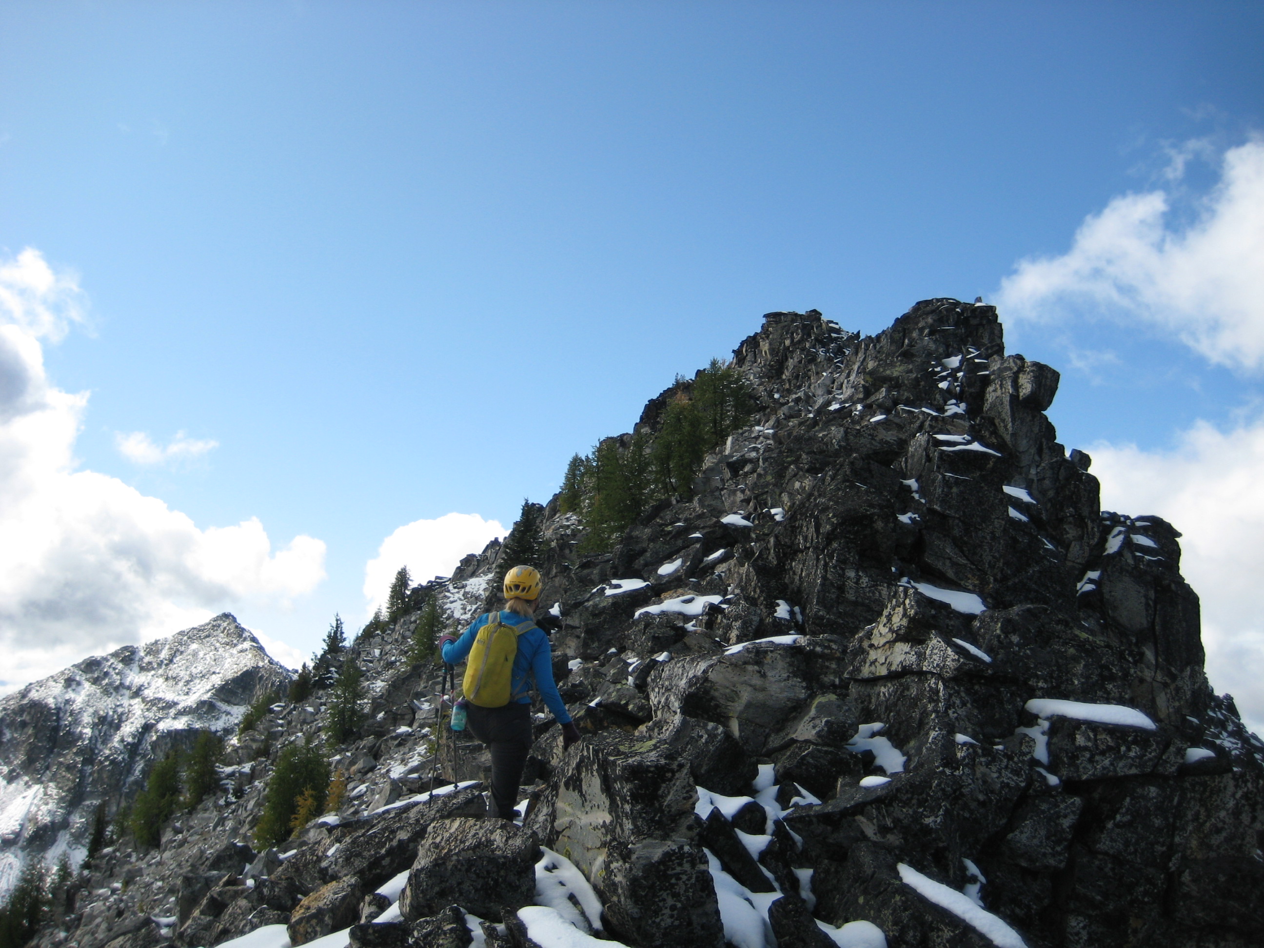 mountain climbers scrambling the rocky, snow dusted Northeast Ridge of Cheops Peak in the Sawtooth Mountains
