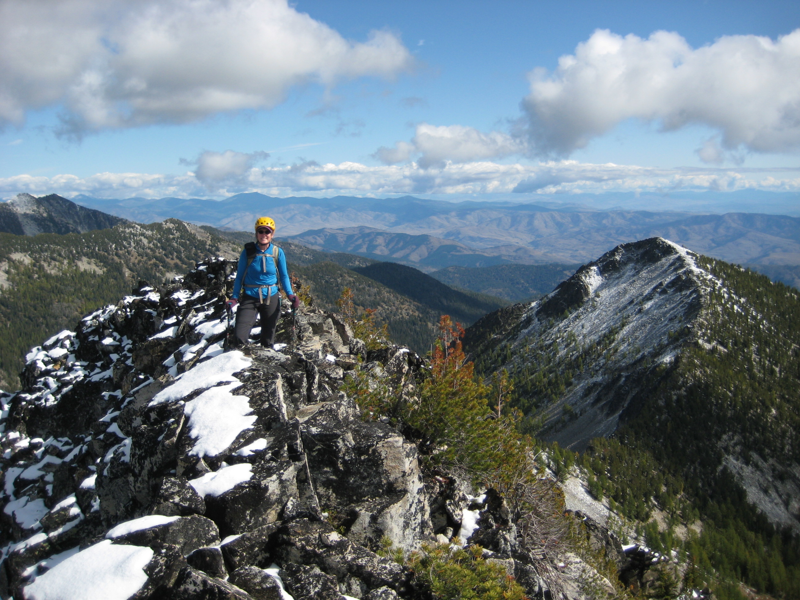 mountain climber on the summit of Cheops Peak with the Sawtooth Mountains in the background