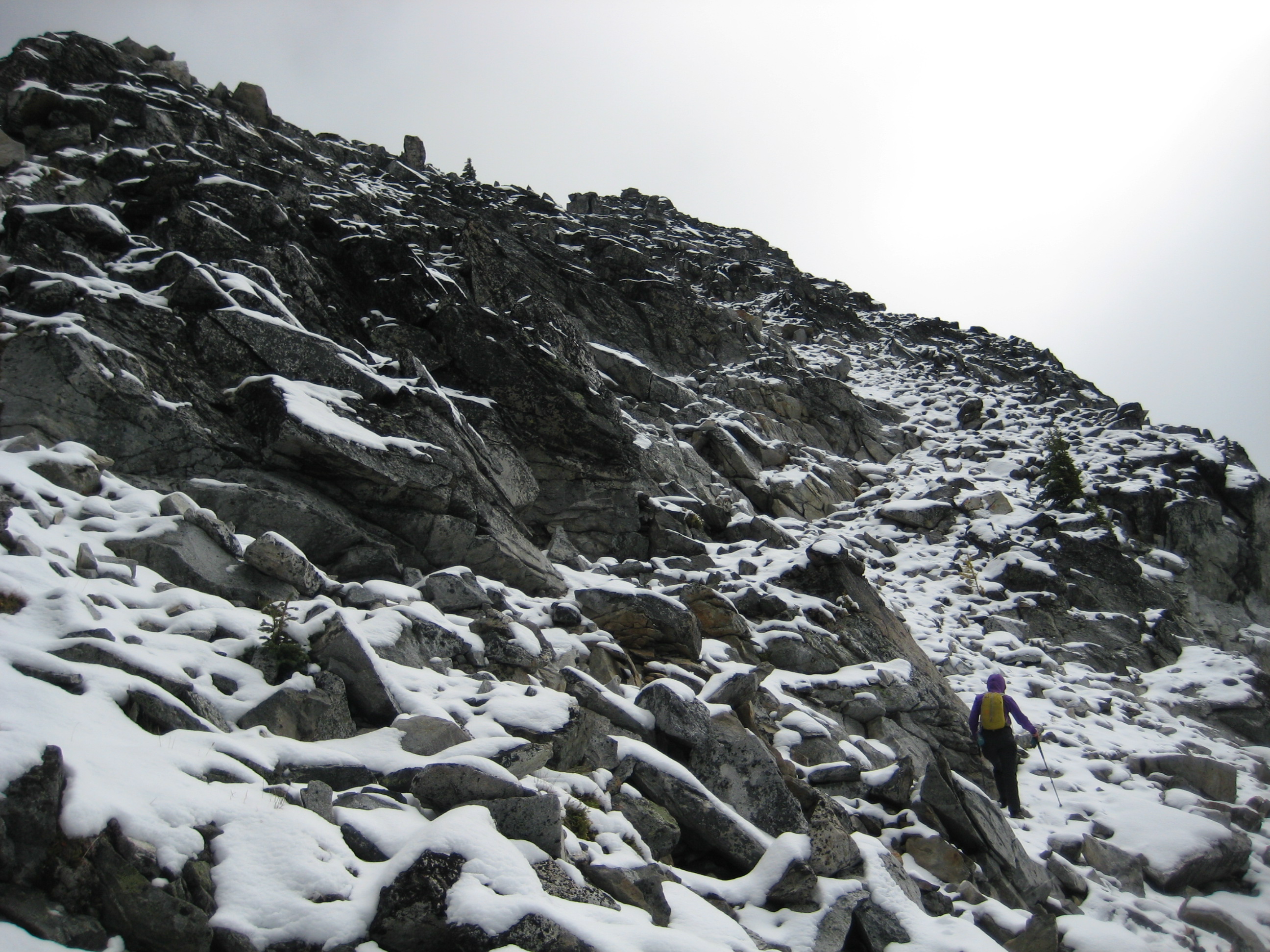 mountain climber scrambling up snow covered boulders on the North Ridge of Martin Peak in the Sawtooth Mountains