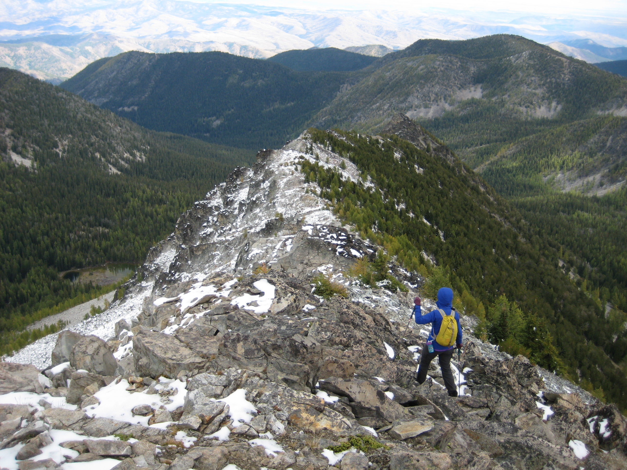 mountain climber scrambling down snow dusted boulder field of Martin Peak in the Sawtooth Mountains