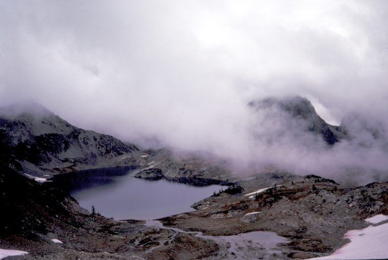 Upper Ice Lakes in the Entiat Mountains in the fog with rocky shores as seen from Freezer Pass