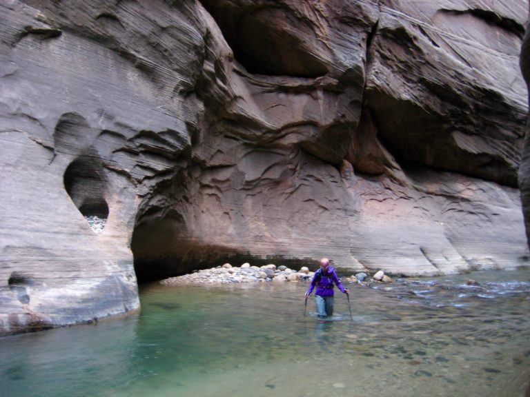 A canyon explorer wades up the Virgin River in Zion Canyon Narrows