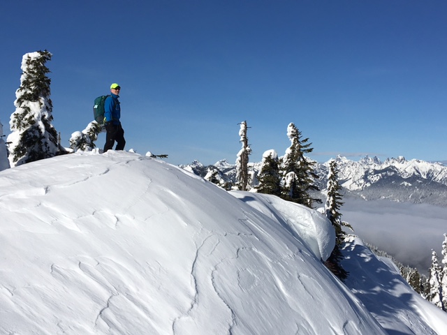 A skier stands atop the summit snow dome of Amabilis Peak during Amabilis Mountain Ski Loop