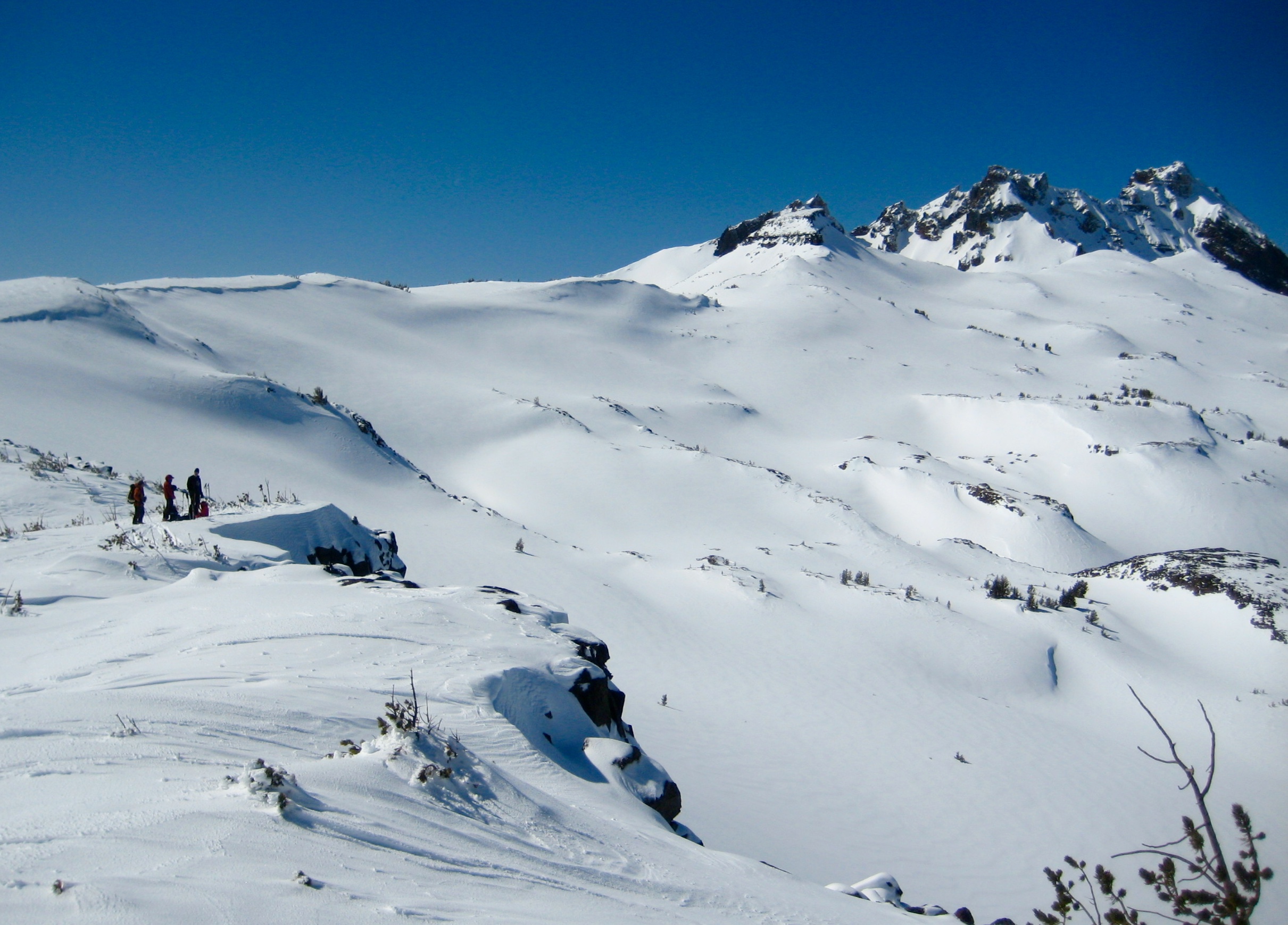 Backcountry skiers on Tam McArthur Rim with Broken Top behind them in the Three Sisters Wilderness