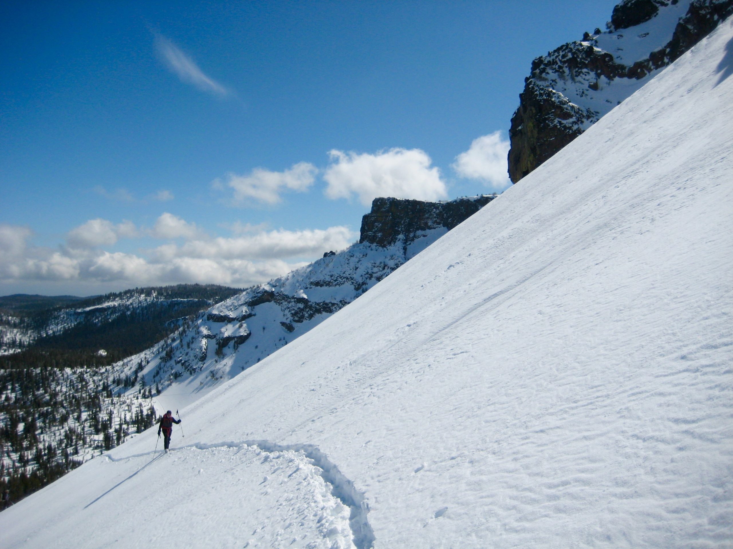 Skier skinning up Yahtzee Bowl with Tam Rim above