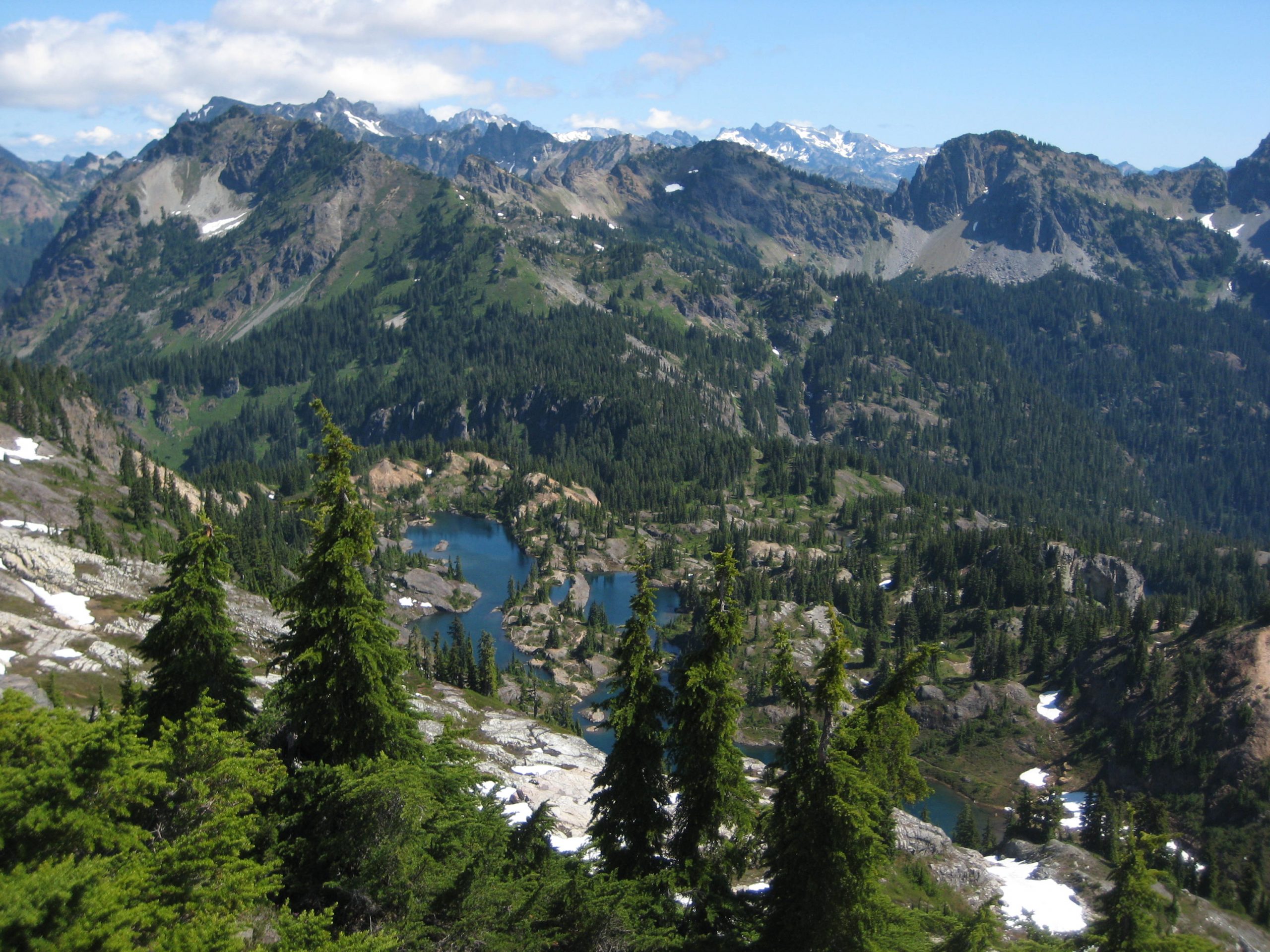 Dark blue Rampart Lakes lie scattered in a large green heather basin below Rampart Peak