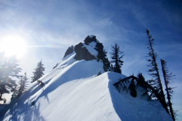 Looking up a knife-edge snow arete at rocky summit of Lichtenberg Mountain near Stevens Pass, WA