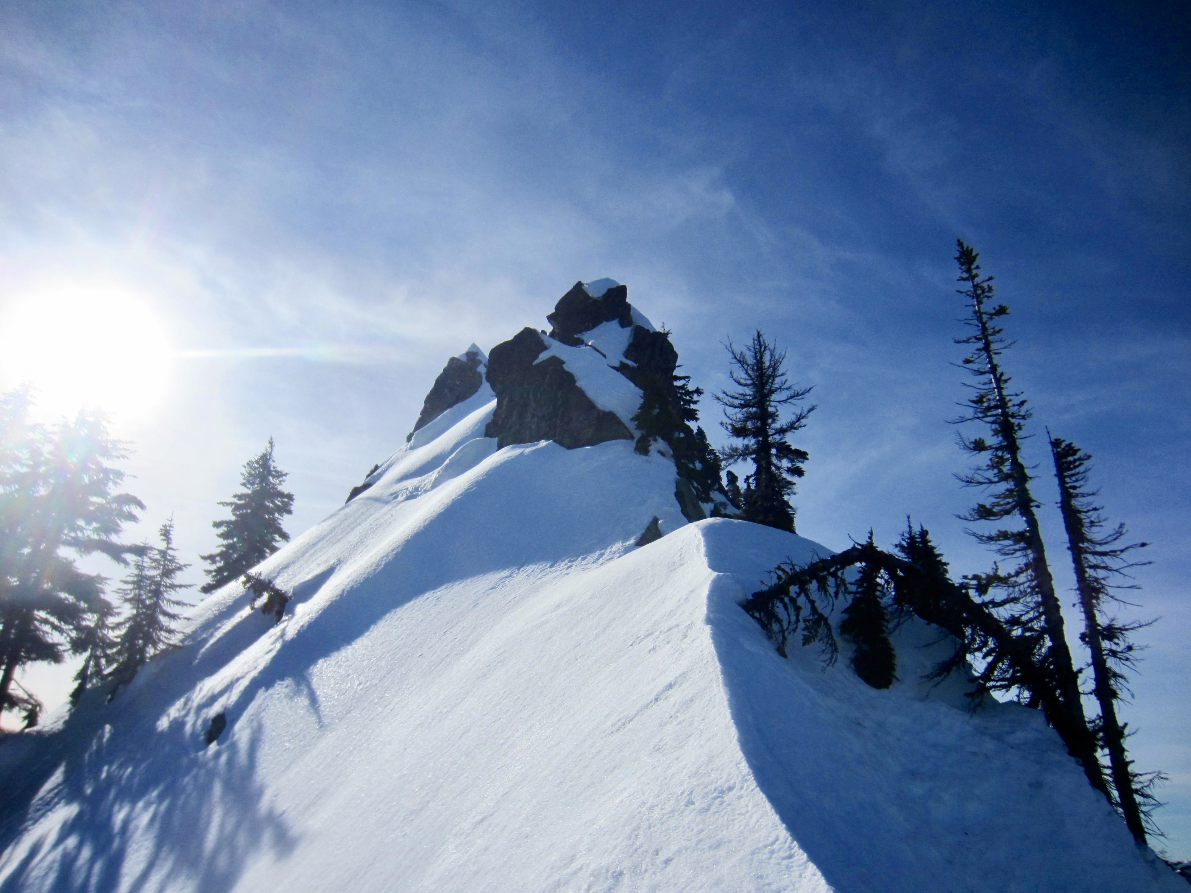 Looking up a knife-edge snow arete at rocky summit of Lichtenberg Mountain near Stevens Pass, WA