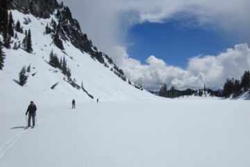 Backcountry skiers glide across the frozen surface of Lake Valhalla during the Nason-Smith Ski Traverse in the Washington Cascades