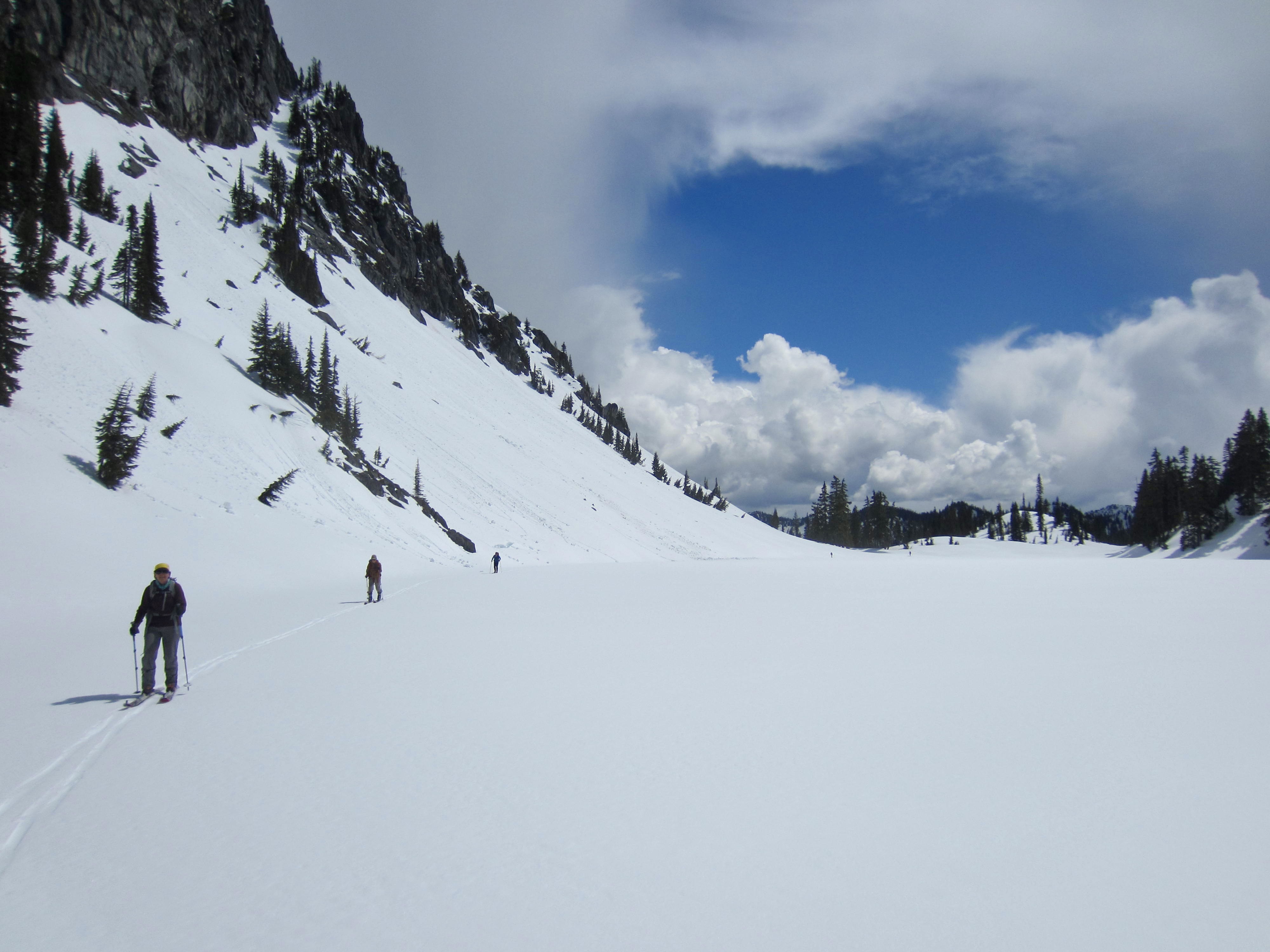 Backcountry skiers glide across the frozen surface of Lake Valhalla during the Nason-Smith Ski Traverse in the Washington Cascades