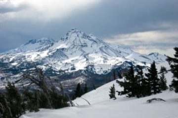 The Three Sisters volcanos rise into a gray sky in the Deschutes Mountains of Central Oregon