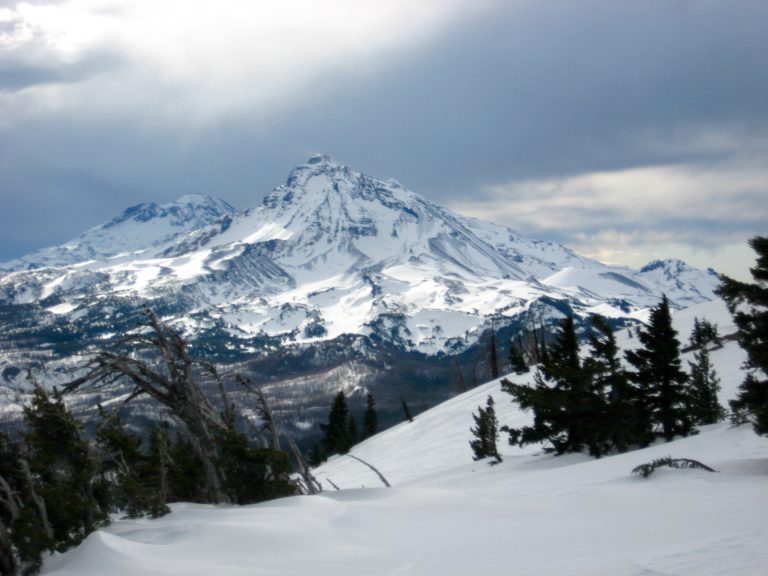 The Three Sisters volcanos rise into a gray sky in the Deschutes Mountains of Central Oregon