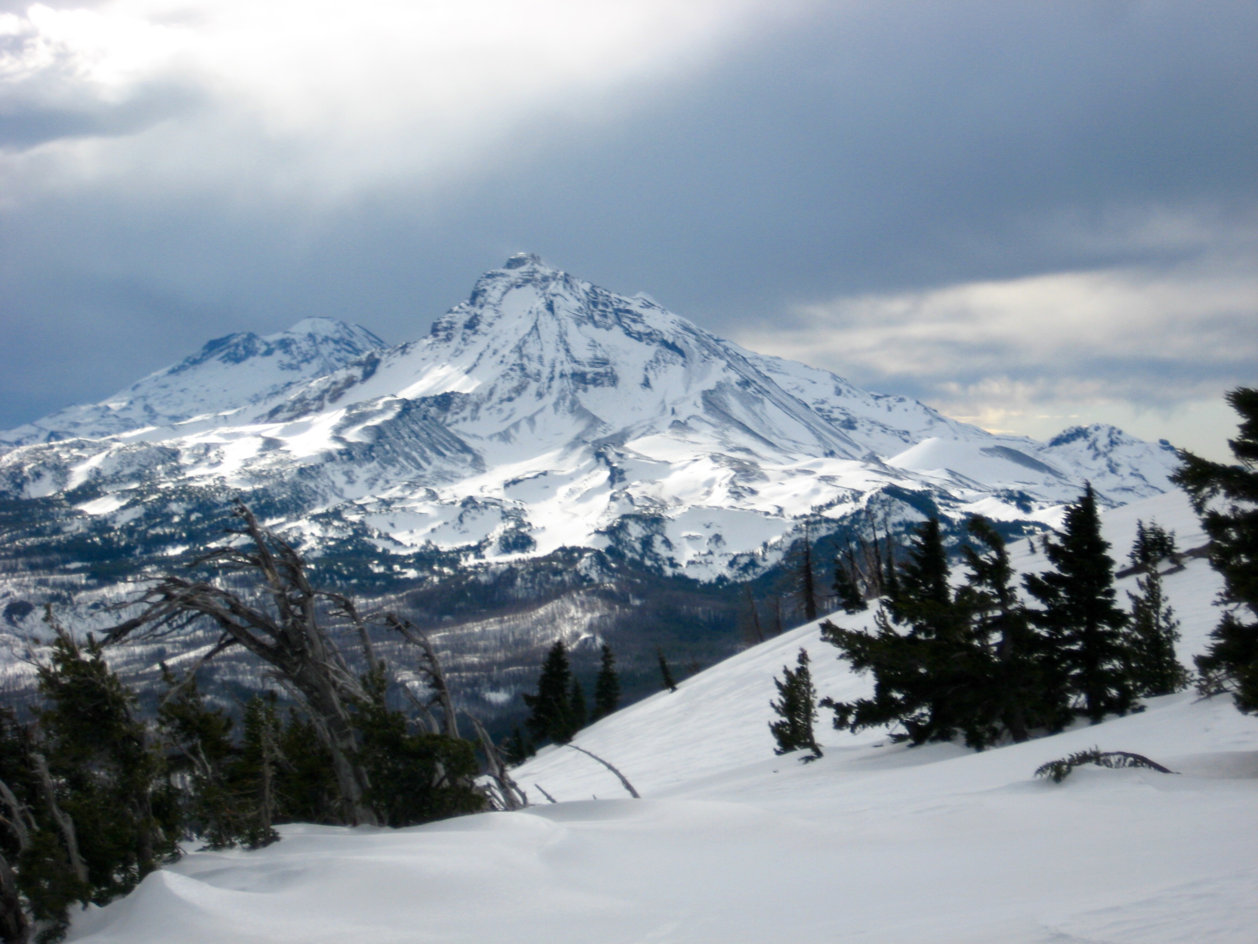 The Three Sisters volcanos rise into a gray sky in the Deschutes Mountains of Central Oregon