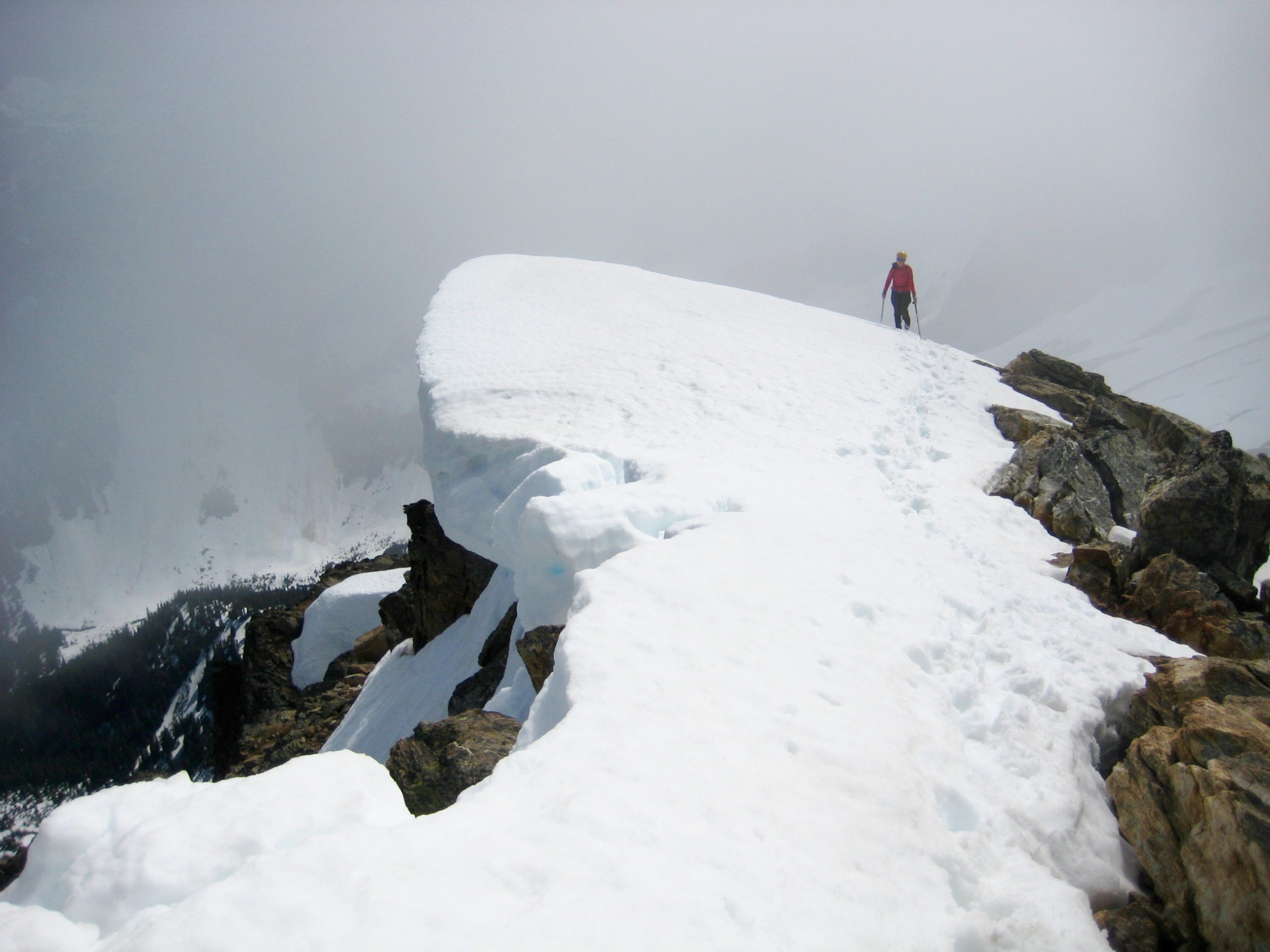 A climber stands atop a snow cornice on the summit of Chiwawa Mountain in the Glacier Peak Wilderness